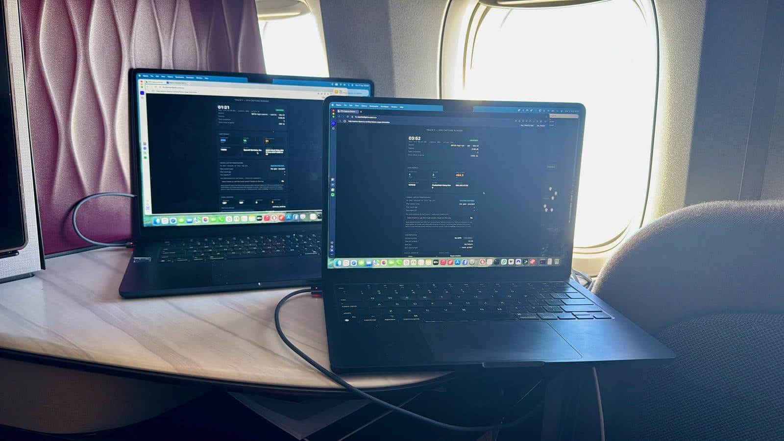 Two laptops running captures on a tray table beside an aircraft window